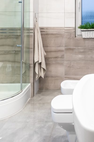 Panorama of spacious and modern bathroom in white and beige with window, walk in shower and classic basin